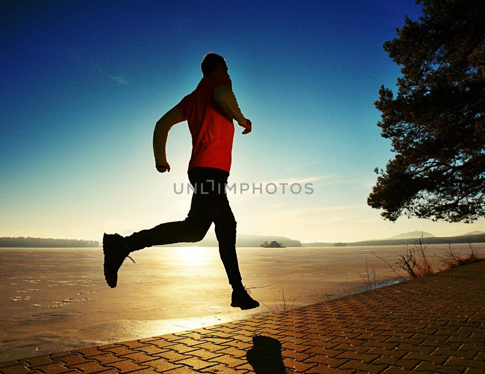 Crazy man jumping while joogging at morning spring lake  by rdonar2