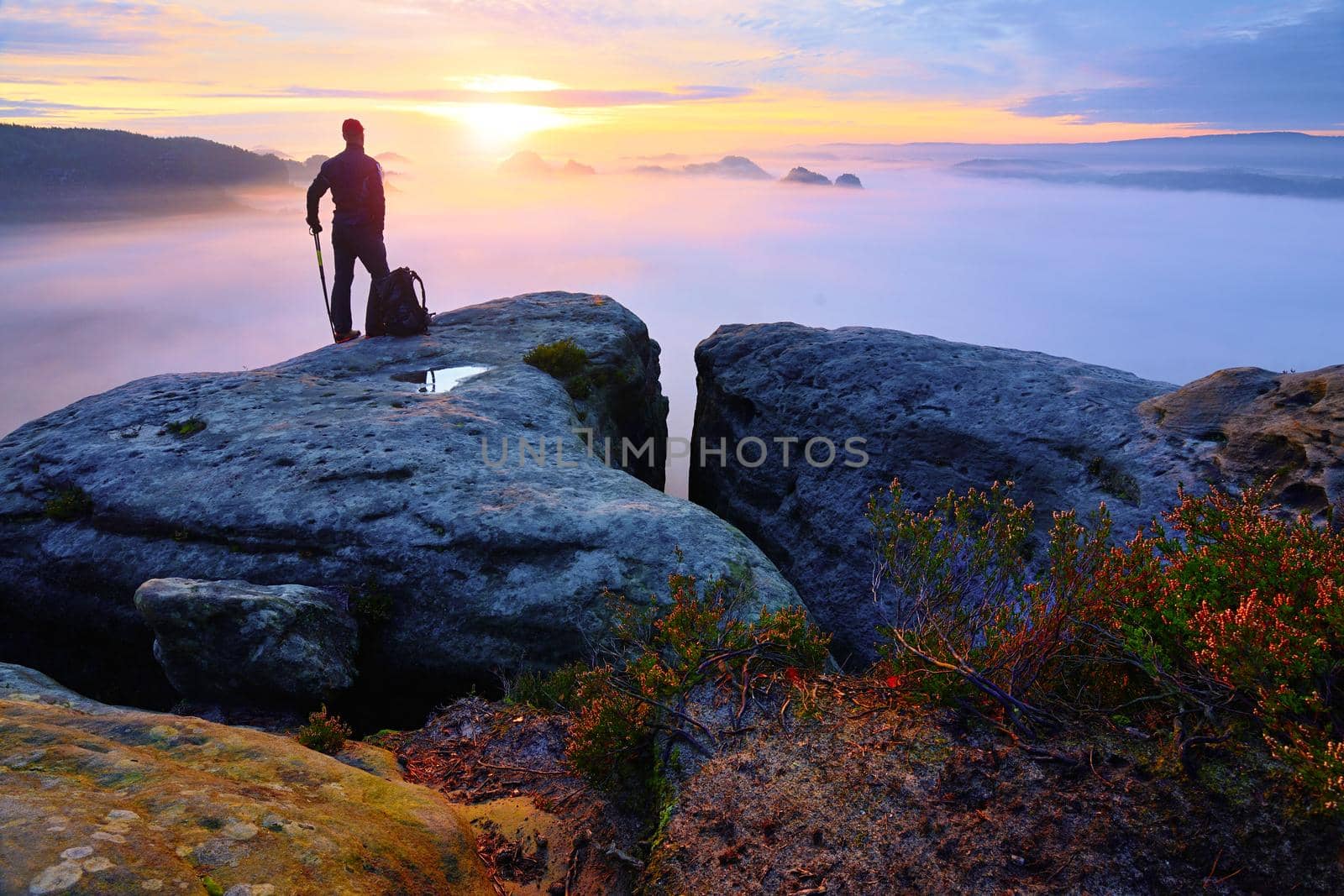 Sharp rear man silhouette on rocky peak. Satisfy hiker enjoy view. Tall man on rocky cliff by rdonar2