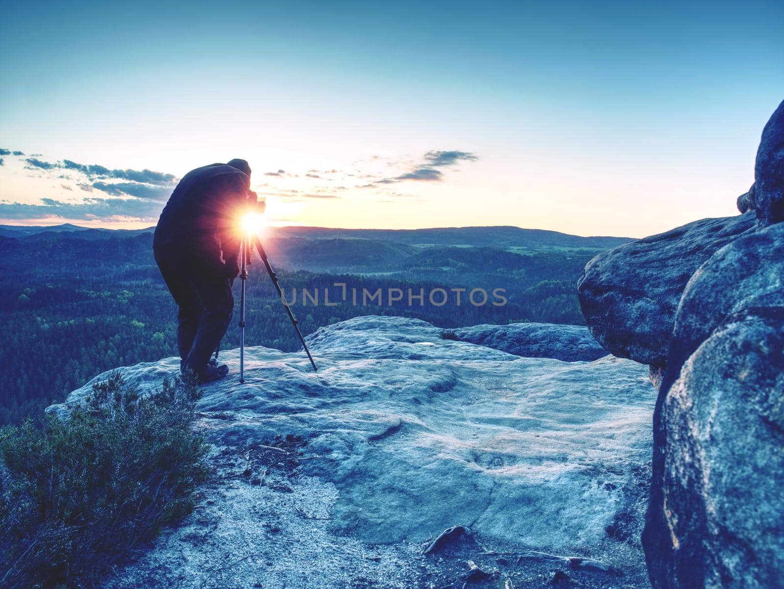 Photographer takes photos with camera on tripod on rock by rdonar2