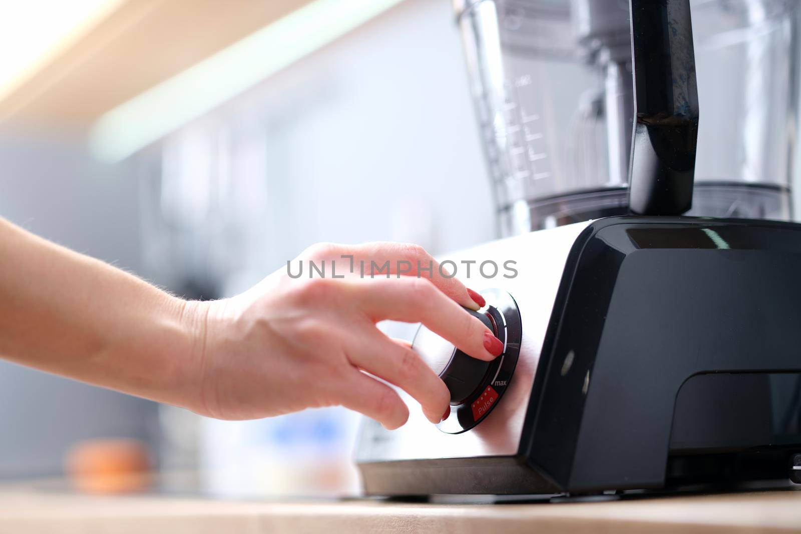 Woman turns on stationary blender to prepare healthy cocktail. Chef turns on blender or multi-combine concept