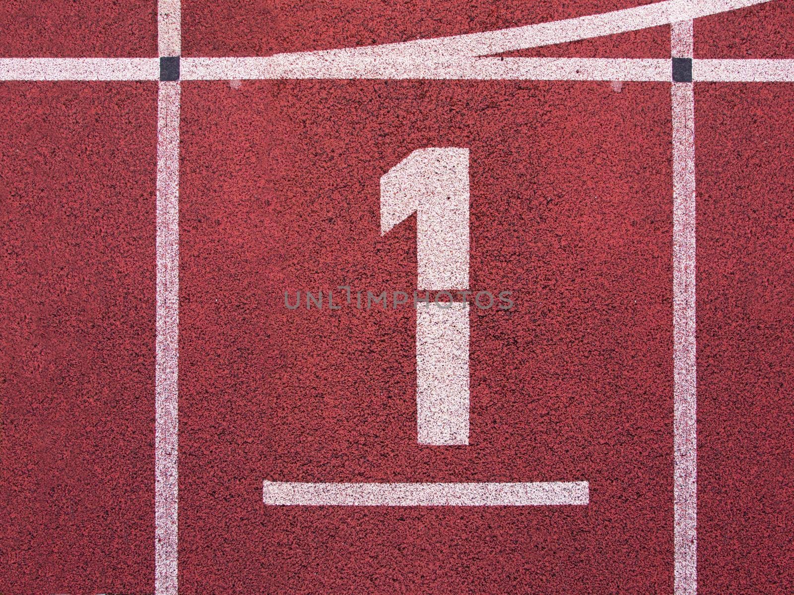 Number one. White track number on red rubber racetrack, texture of running racetracks in small stadium