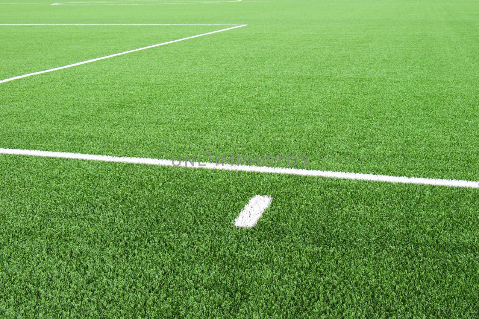 White lines on football playground. Detail of lines in a soccer field. Plastic grass and finely ground black rubber.  by rdonar2