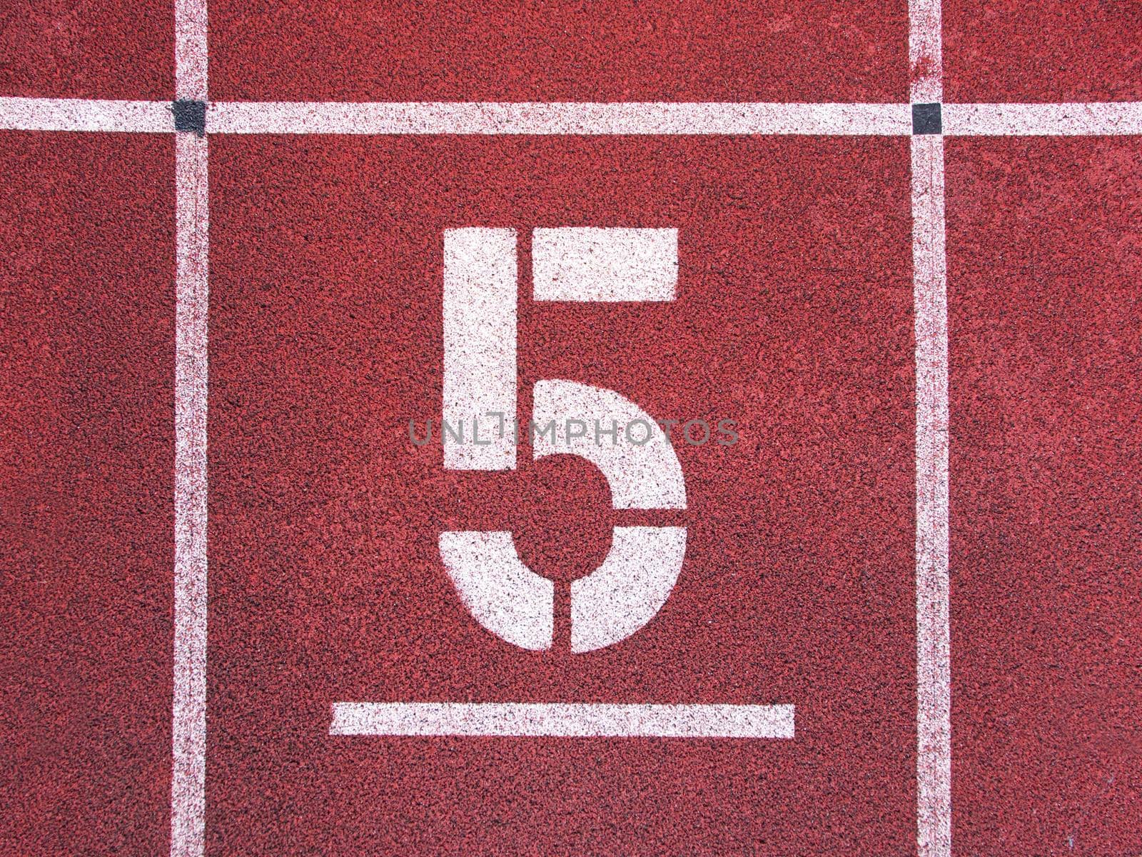 Number five. Big white track number on red rubber racetrack. Gentle textured running racetracks in athletic outdoor stadium. by rdonar2