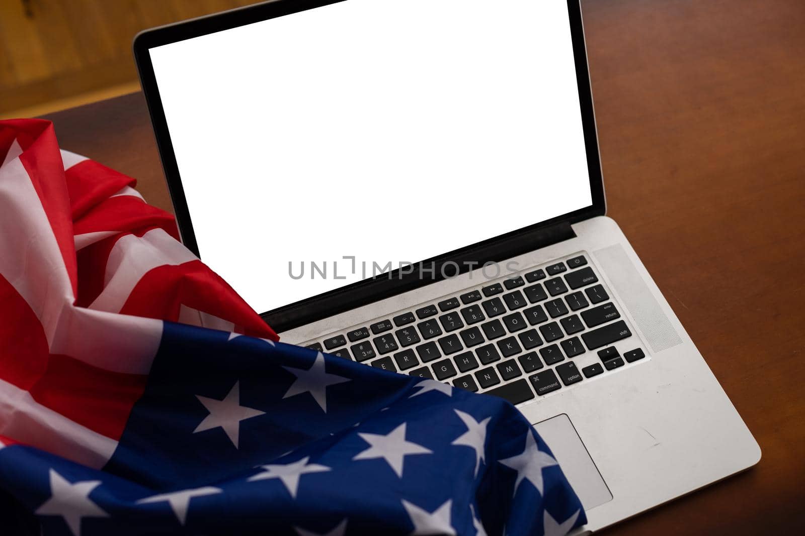 Laptop with blank screen and USA flag on desk in office by Andelov13