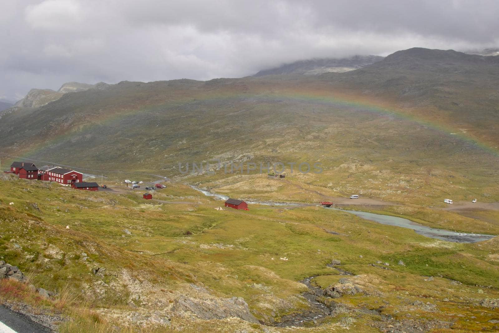 Landscape showing a rainbow over a beautiful valley with some houses in Norway