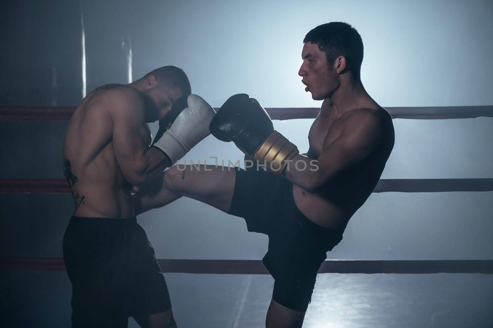 Two shirtless muscular man fighting Kick boxing combat in boxing ring. by HERRAEZ