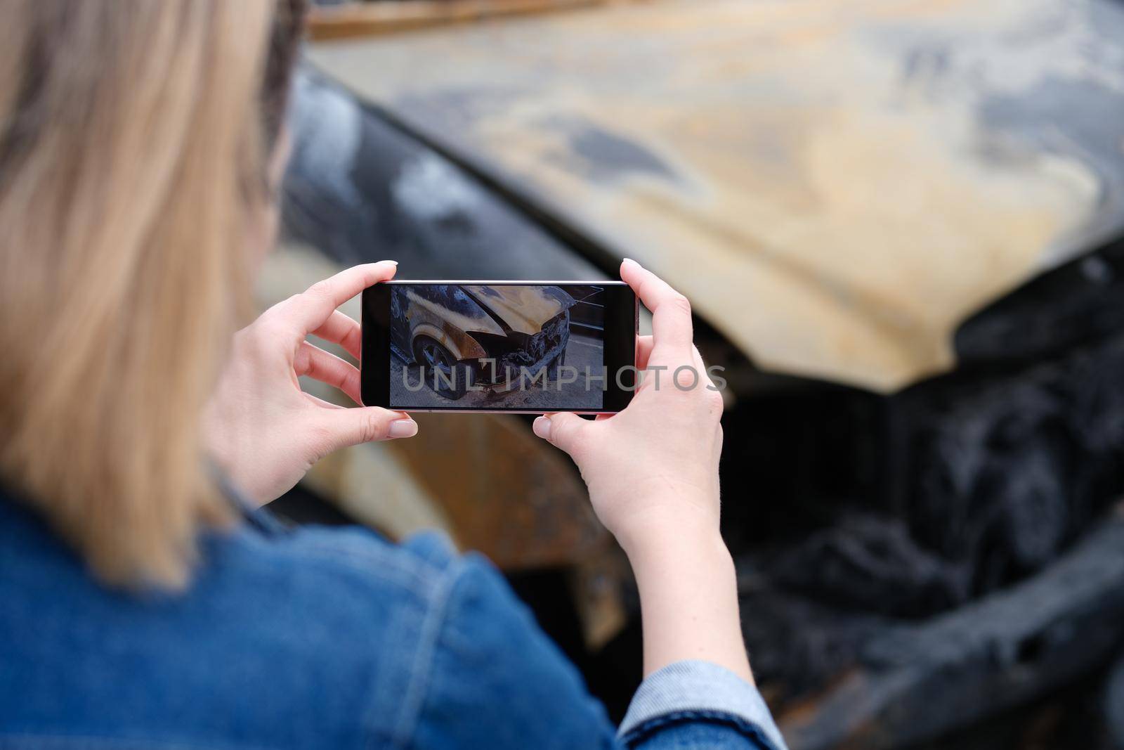 insurance agent or investigator takes picture on smartphone of car after arson. Transport insurance or criminal offense concept