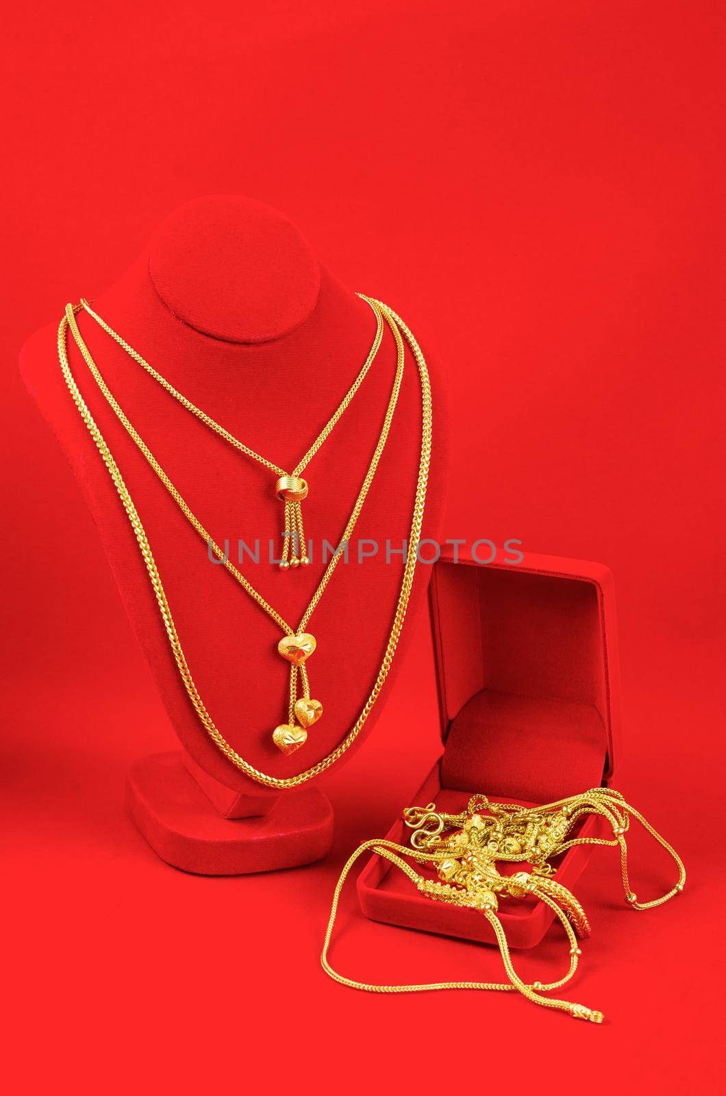 Necklace display stand with gold necklace on red Velvet fabric. by Gamjai