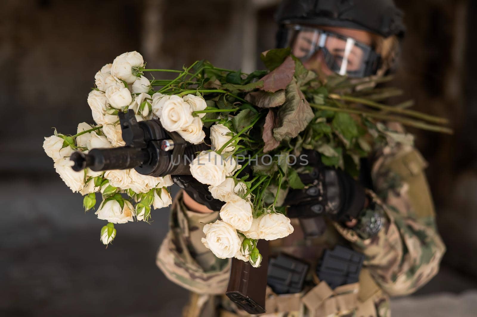 Caucasian woman in military uniform holding a machine gun and a bouquet of white roses