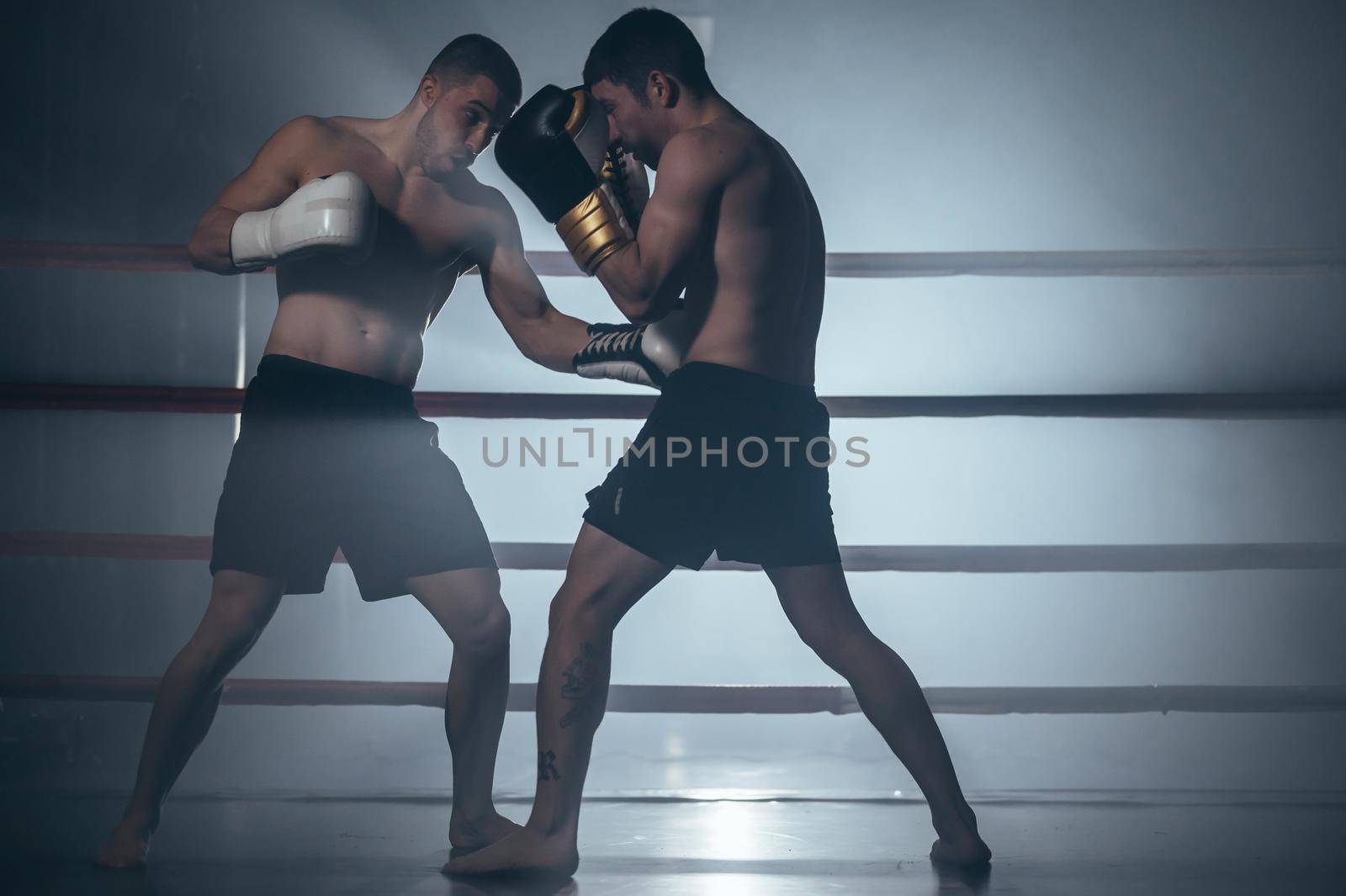 Two shirtless muscular man fighting Kick boxing combat in boxing ring. High quality photo