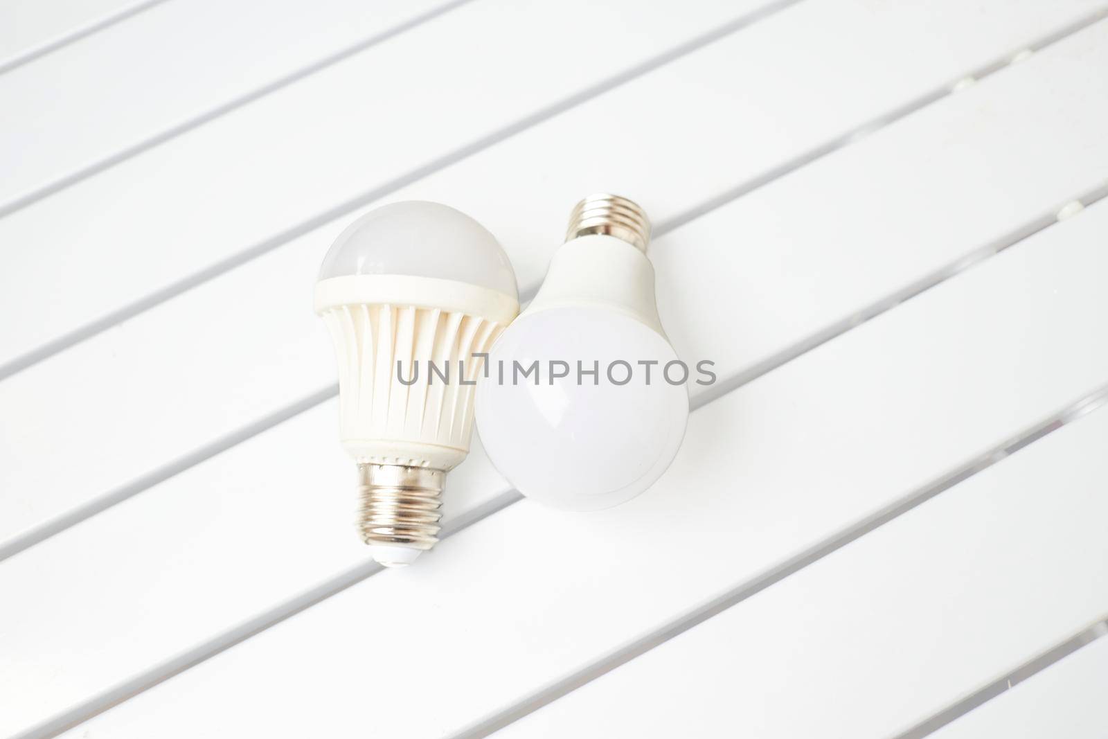 Two LED bulbs on a striped table by jovani68