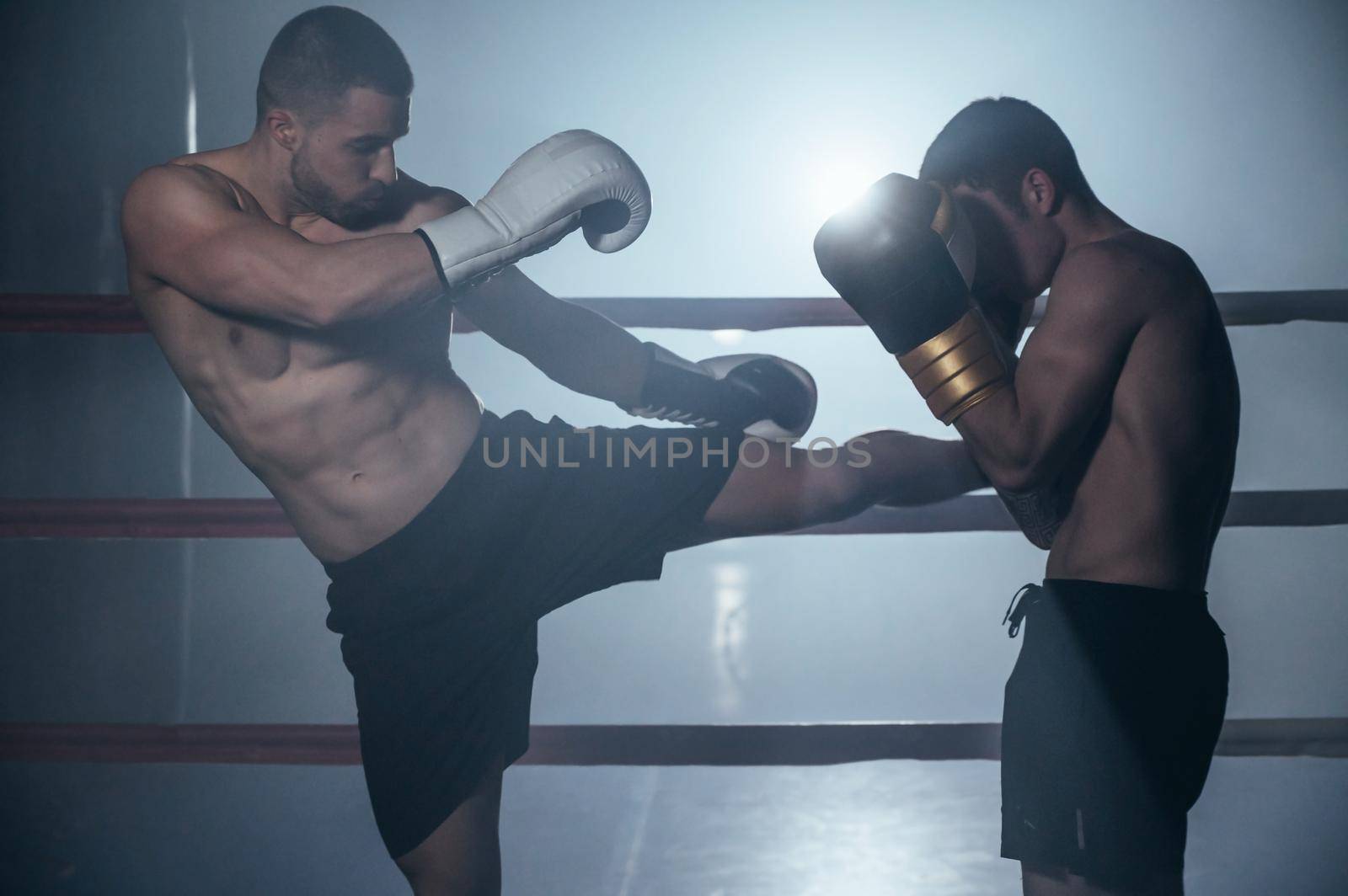 Two shirtless muscular man fighting Kick boxing combat in boxing ring. by HERRAEZ