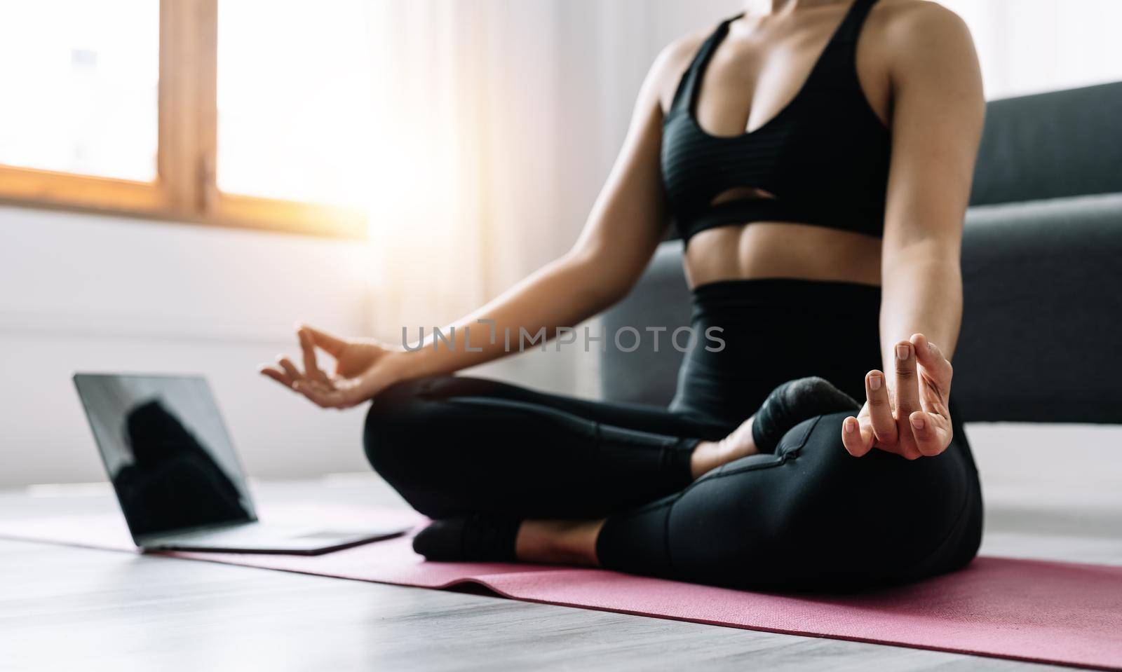 Young woman exercising, asian woman practicing meditation indoors from laptop, Yoga and Healthy lifestyle concept. by nateemee