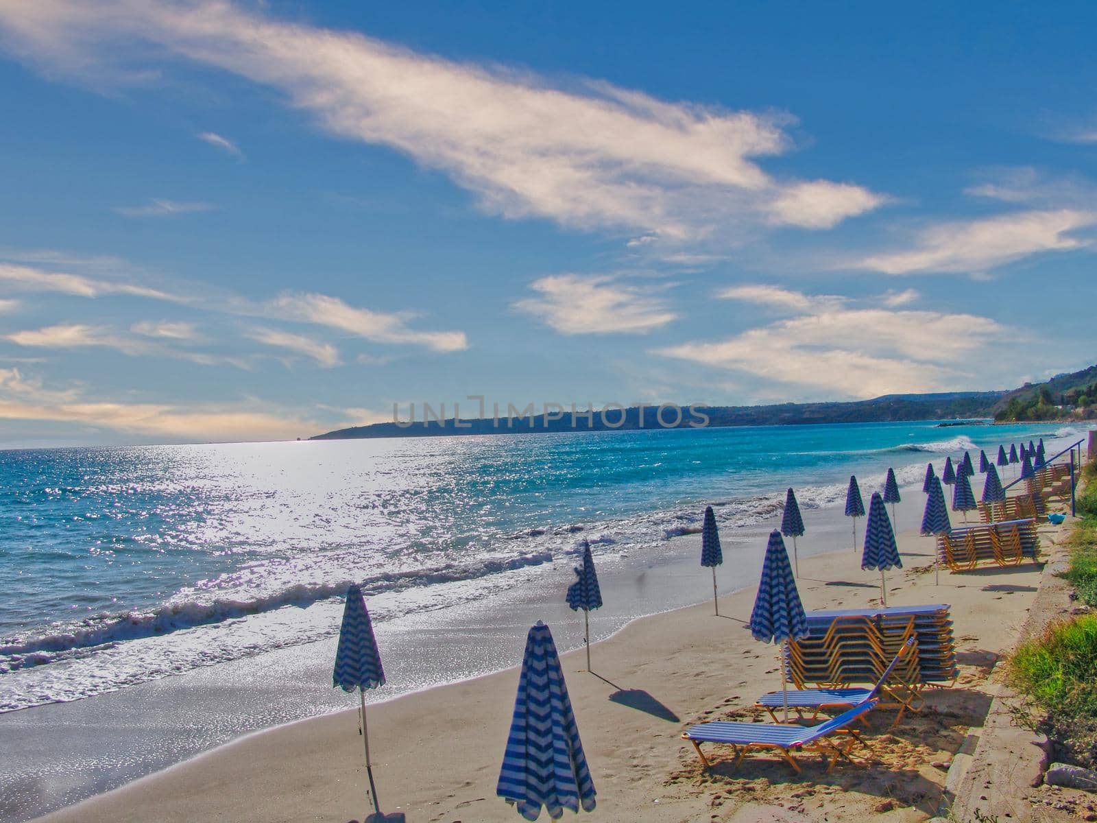 Pair of sun loungers and a beach umbrella on a deserted beach in Kefalonia island