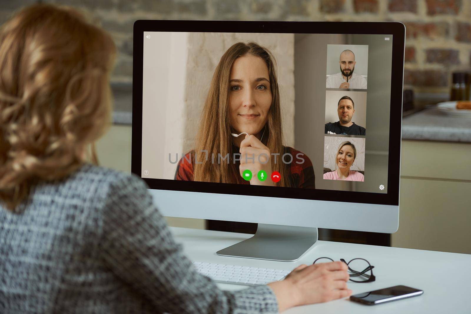 A desktop computer screen view over a woman's shoulder. A boss works remotely listening to a report of employee on an online briefing. A female teacher listening to a student on a video call.