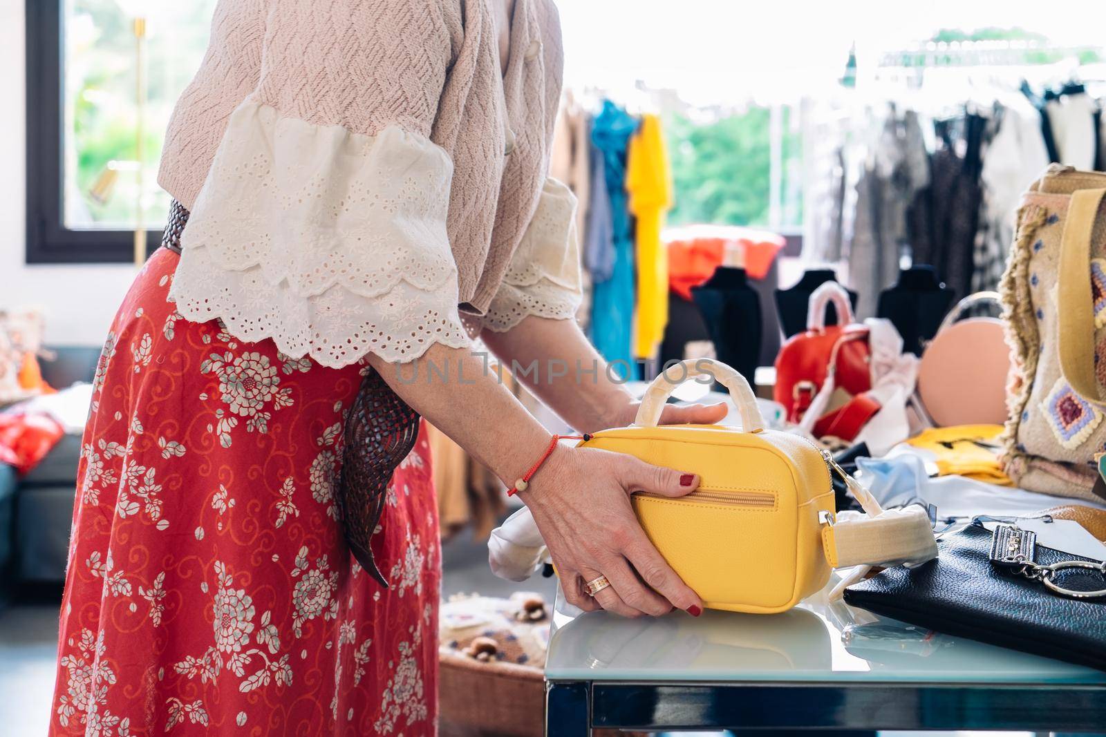 cutout shot of a woman picking up a handbag to buy it in a fashion shop. shopping concept. by CatPhotography