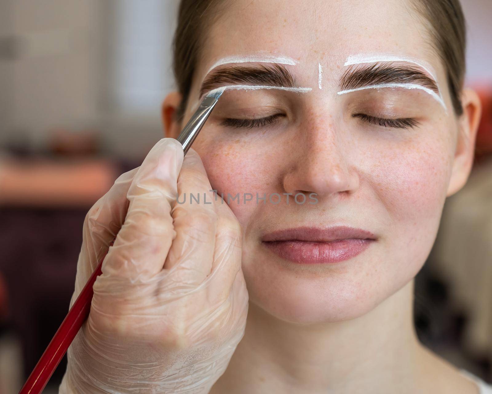 The master draws the shape of the eyebrows with white paint before coloring