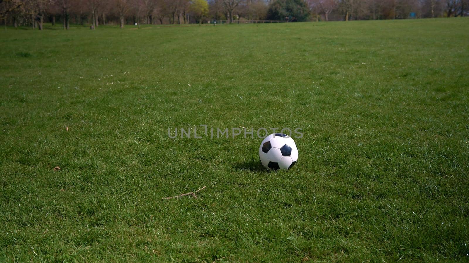 Panorama Wide Shot Black White Classic Soccer Ball On Green Grass. Happy Family Of Children Having Fun In Spring Park. People Playing Football. Sport, Healthy Life, Championship, Competitions Concept by mytrykau