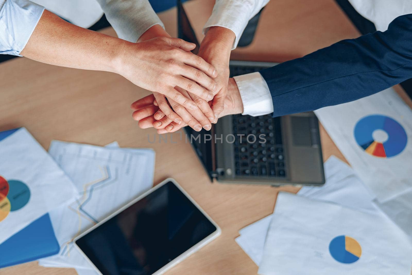 Young business people working at office are holding hands together top view close-up teamwork.