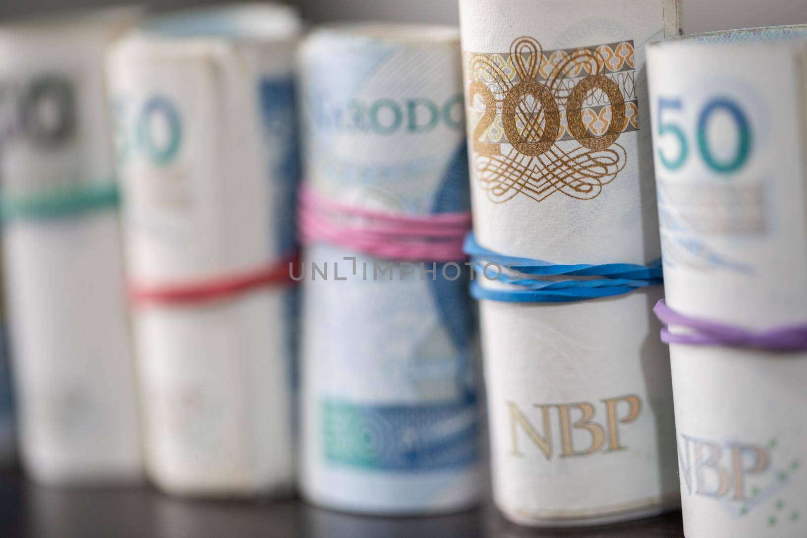 An accumulated supply of cash rolled up in rolls and fastened with a rubber band. Polish national paper cash.