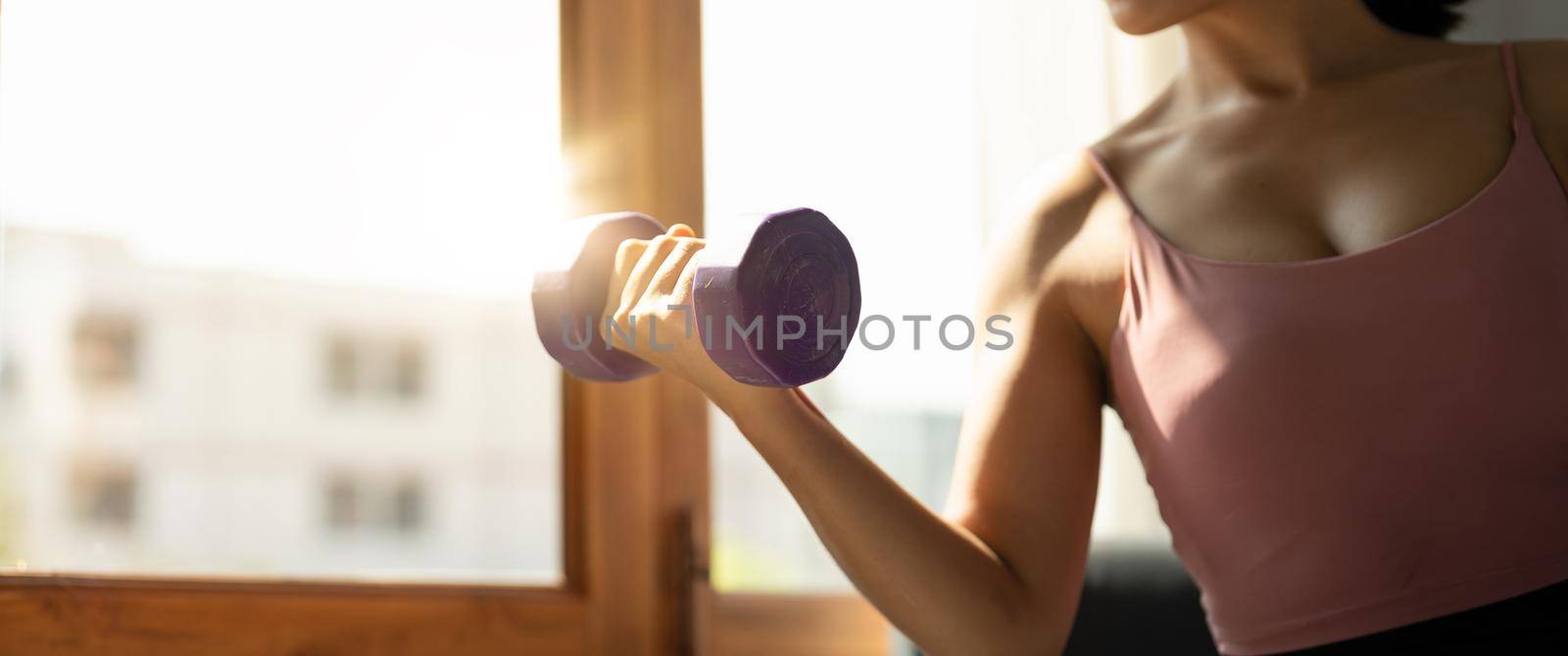Close up of young asian woman lifting dumbbells at home.