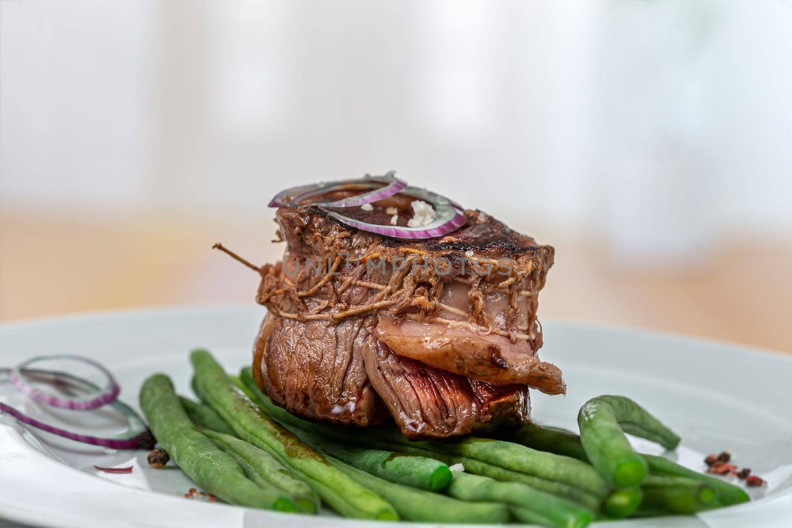 Top view of a grilled tournedos accompanied by green beans.
