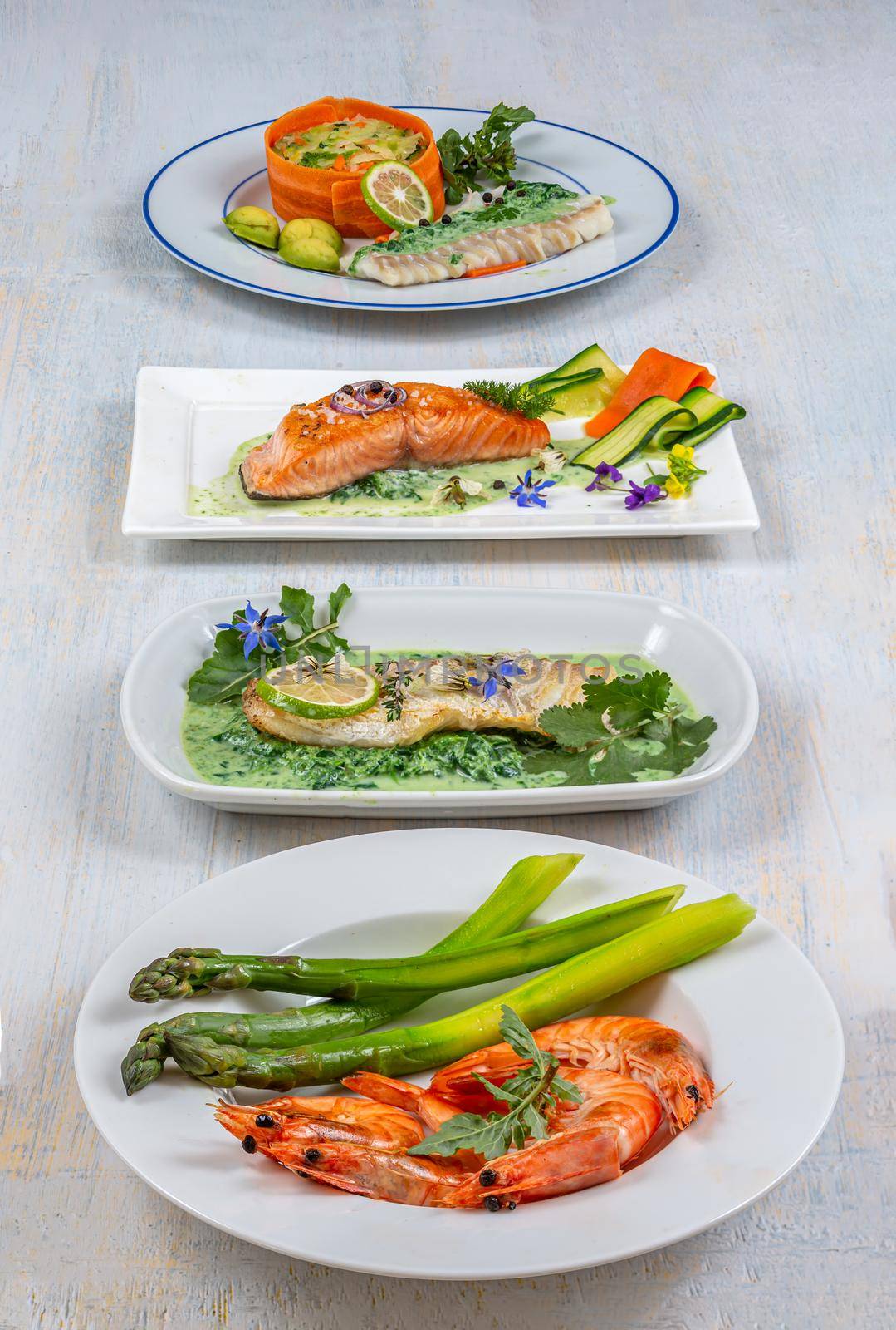Cod, salmon, shrimp, vegetable assotis in plates in a row.