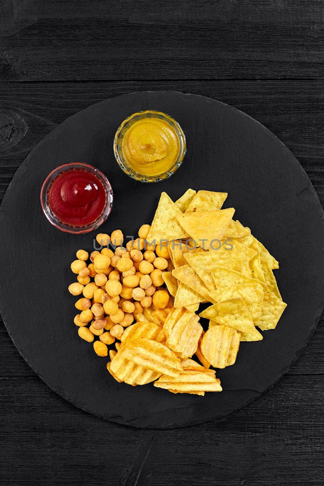 Overhead view of snacks with sauce on black wooden table. Top view. Copy space. Still life. Flat lay