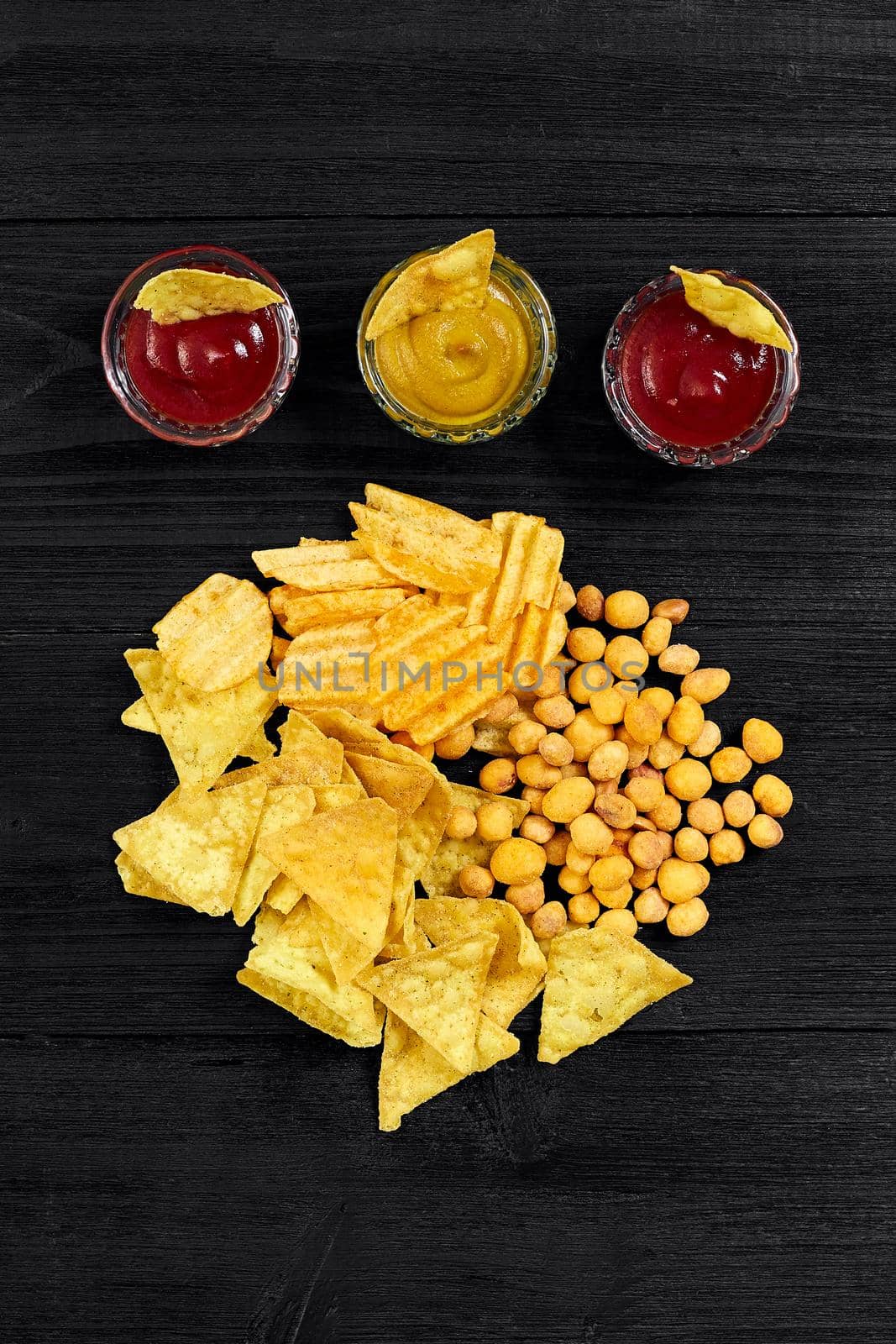 Overhead view of snacks with sauce on black wooden table. Top view. Copy space. Still life. Flat lay