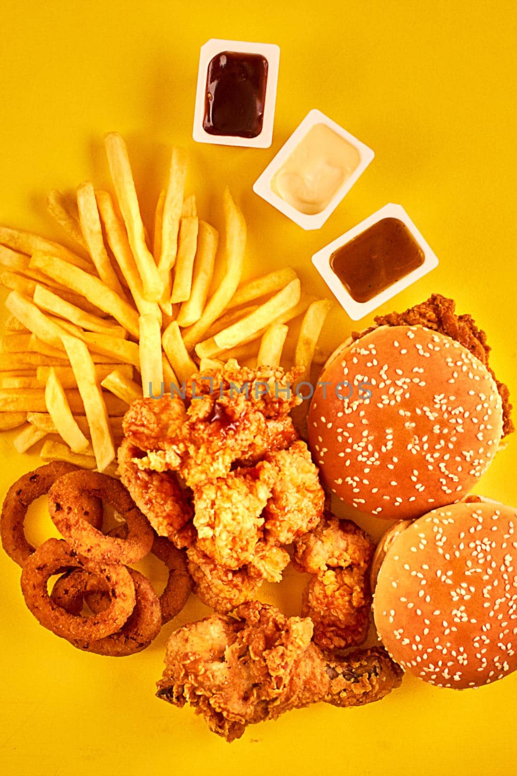 Top view hamburger, french fries and fried chicken on yellow background. Copy space for your text. Still life. Flat lay. Menu or receipt background