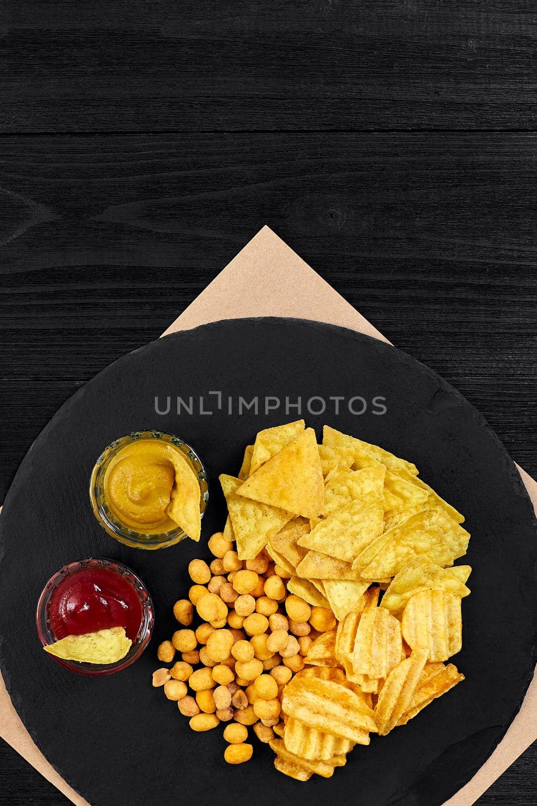 Wide selection of snacks for beer with different sauces on parchment top view. Copy space. Still life. Flat lay