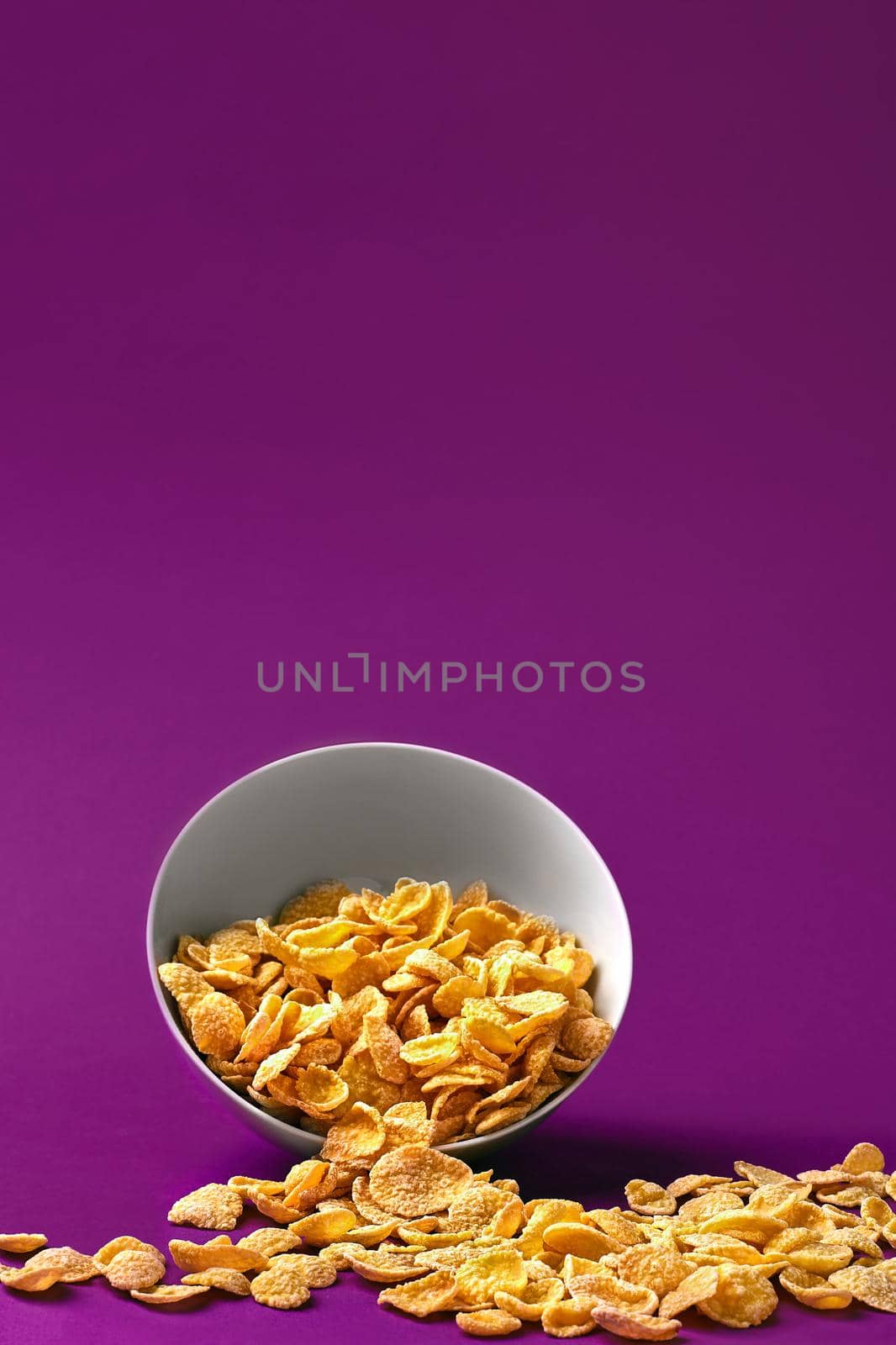 Bowl with cornflakes on the colorful background. Purple background. Copy space. Still life. Flat lay