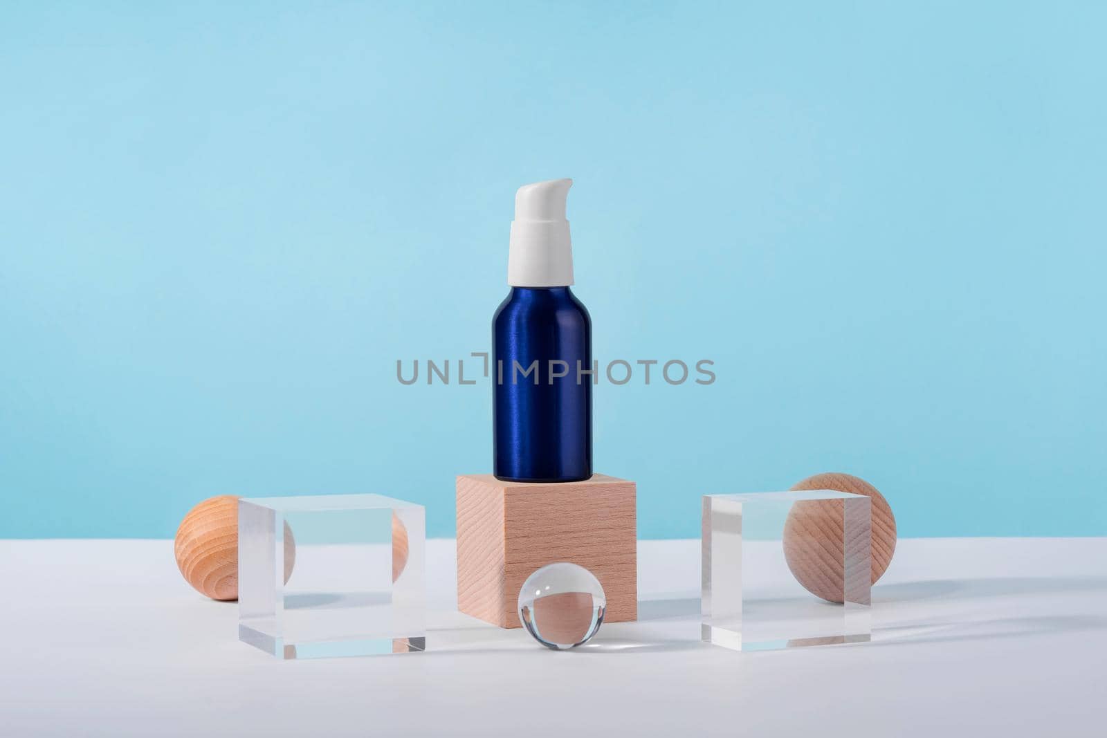 Cosmetic cream metallic pump bottle mockup on blue background with stylish props on acrylic pedestal podium. Unbranded lotion white beauty product packaging. Product presentation by photolime