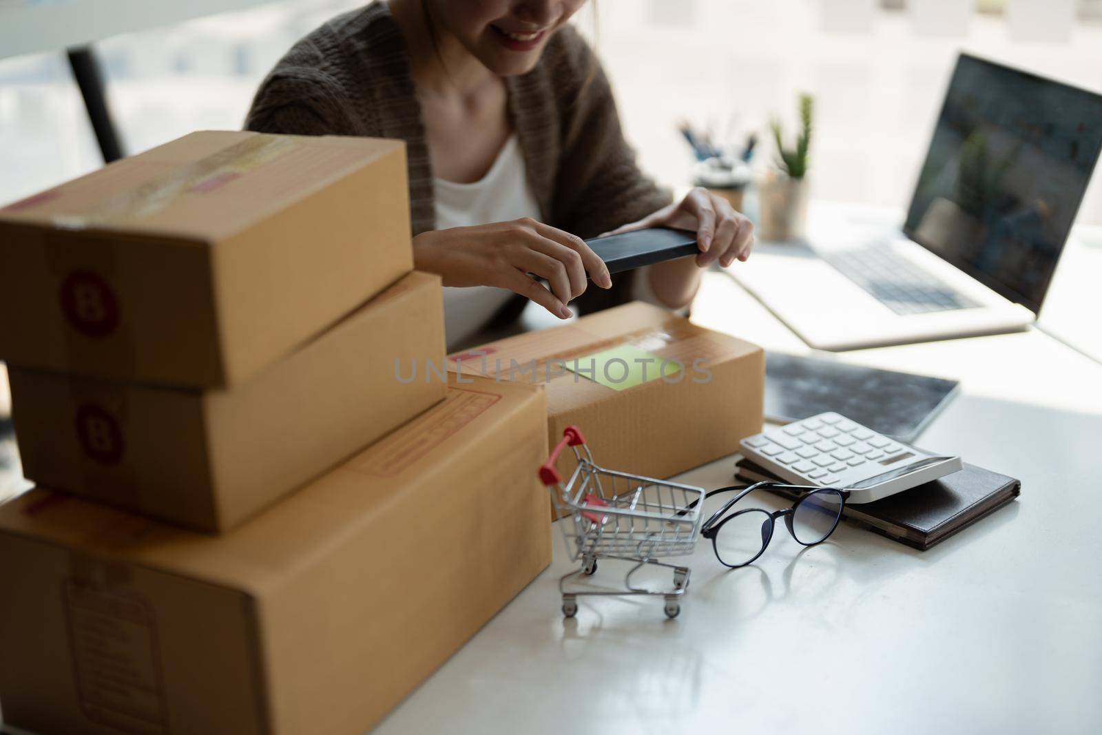 Young asian businesswoman owner packing and take a photo on cardboard box, Young Owner Woman Start up for Business Online. People with online shopping SME entrepreneur or freelance working concept.