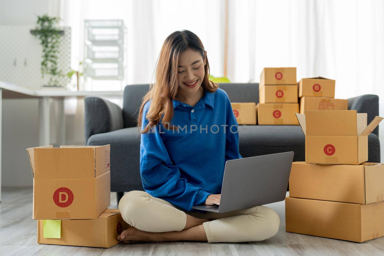 Startup SME small business entrepreneur, holding card box standing at her home office. Beautiful success Asian businesswoman online marketing, SME preparing package parcel delivery to her customer.