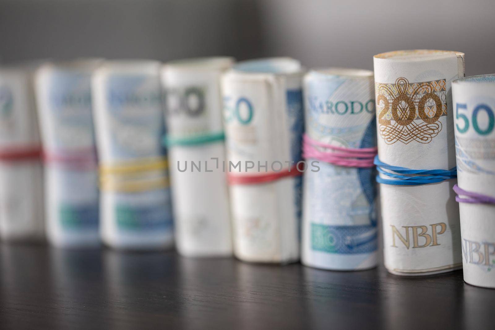An accumulated supply of cash rolled up in rolls and fastened with a rubber band. Polish national paper cash.
