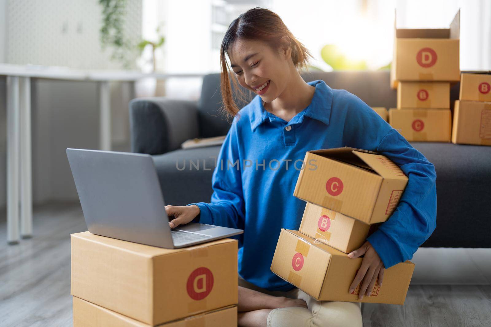 Attractive Asian woman online working in office desk use laptop computer, online marketing packaging box delivery, SME e-commerce concept.