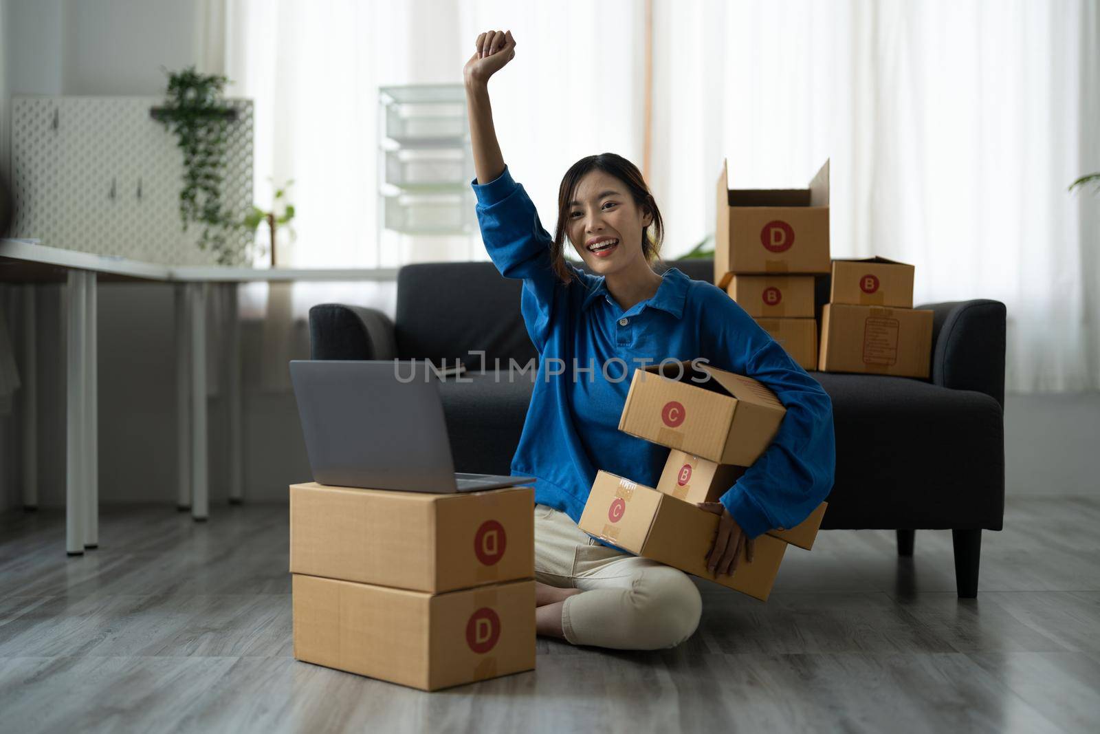 Attractive Asian woman online working in office desk use laptop computer, online marketing packaging box delivery, SME e-commerce concept.