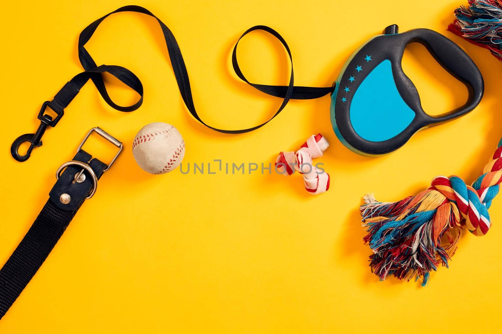 Toys -multi coloured rope, ball, leather leash and bone. Accessories for play and training on yellow background top view by nazarovsergey