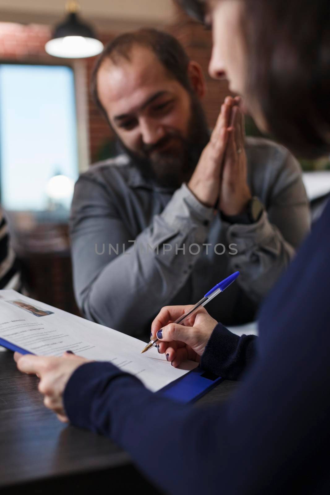 Startup company recruiter reviewing smiling job candidate CV while sitting in office space. Thankful applicant smiling heartily because of career oportunity while woman reading man resume.