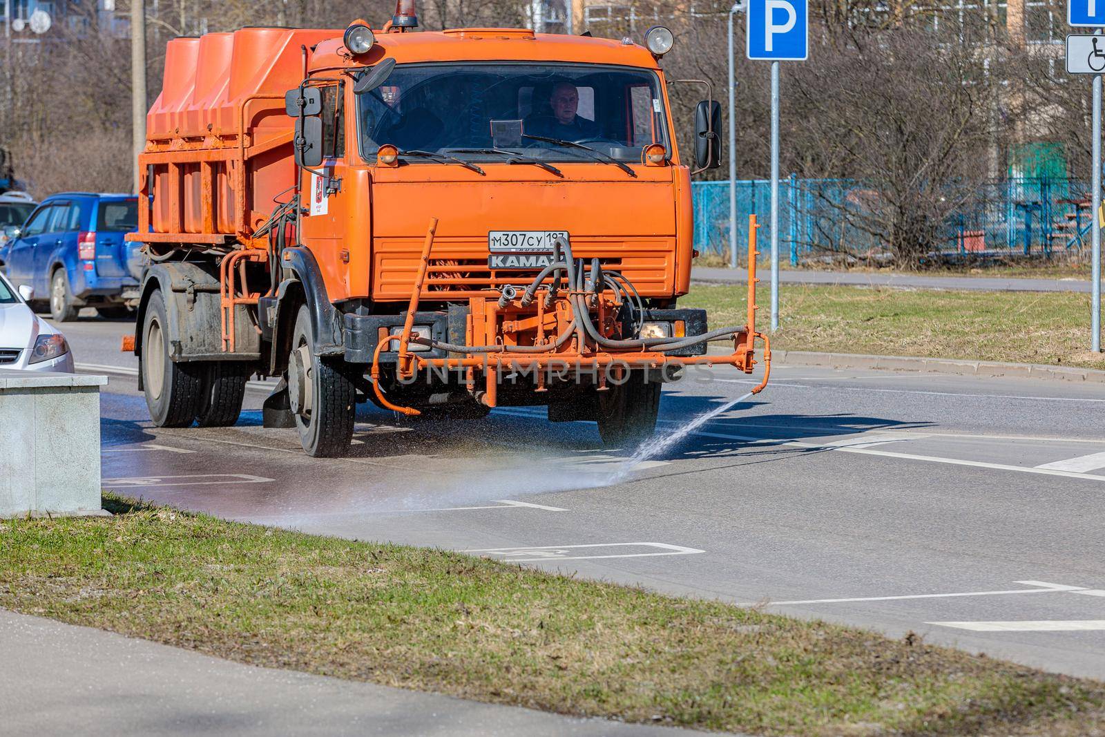 A transport service car washes the road with water from a hose. The machine washes away dirt and road dust. Moscow Russia April 14, 2022.