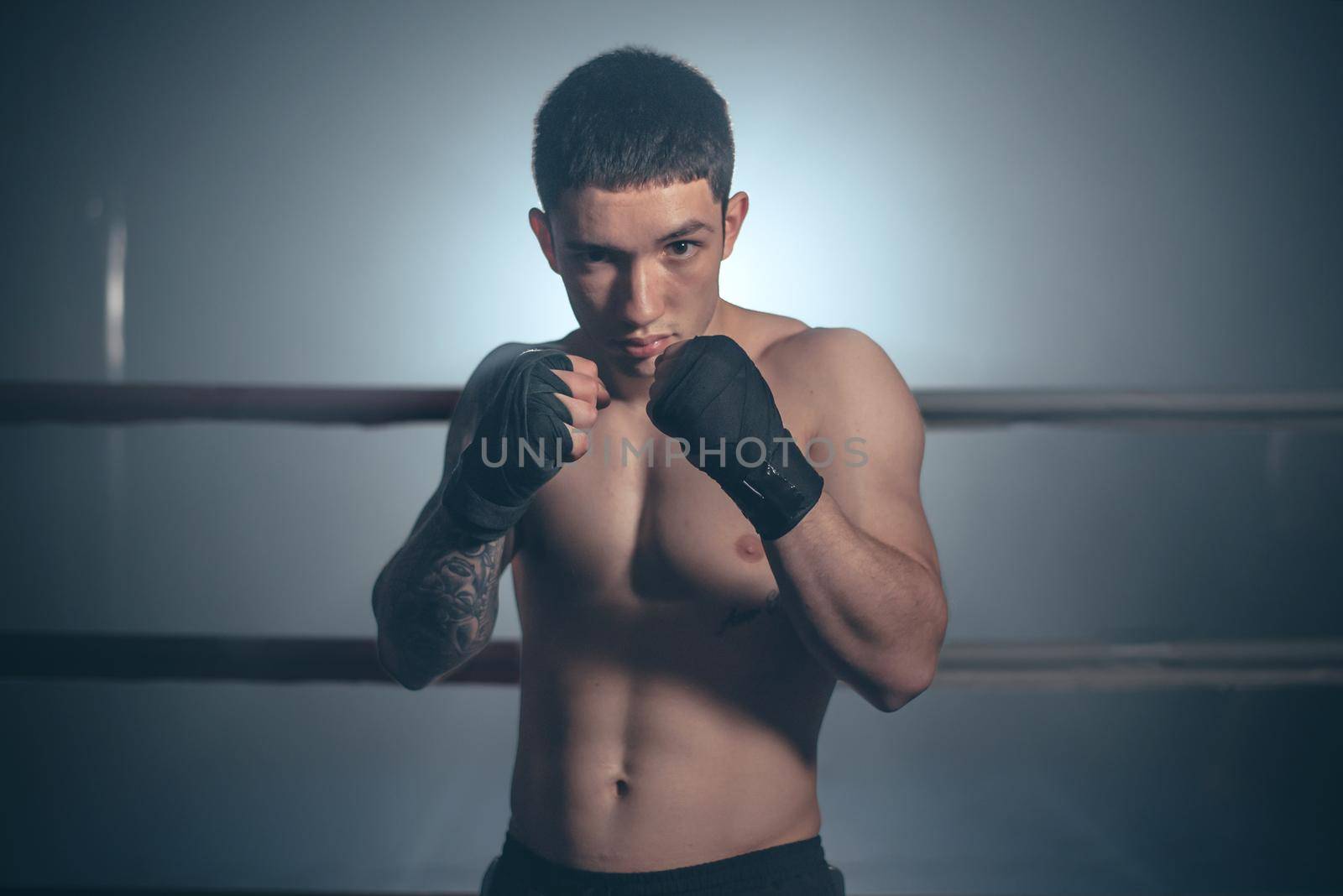 Boxer, man posing in bandage on boxing ring. Fitness and boxing concept. by HERRAEZ