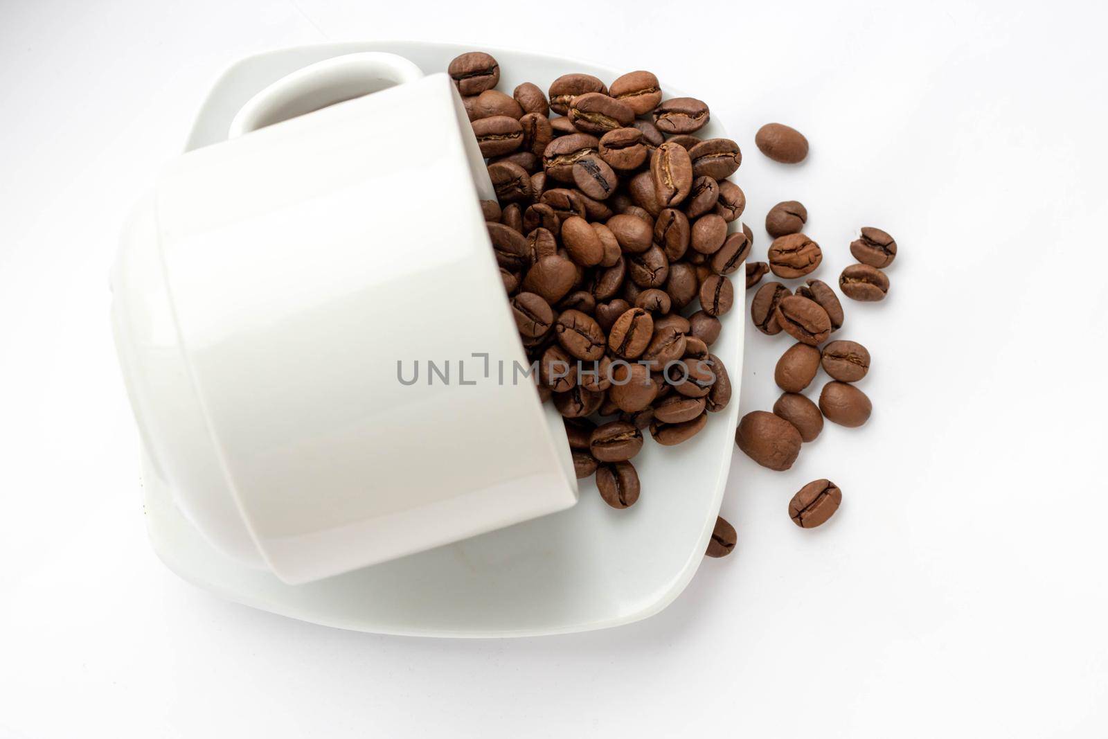coffee beans spilled out of a cup isolated on white background
