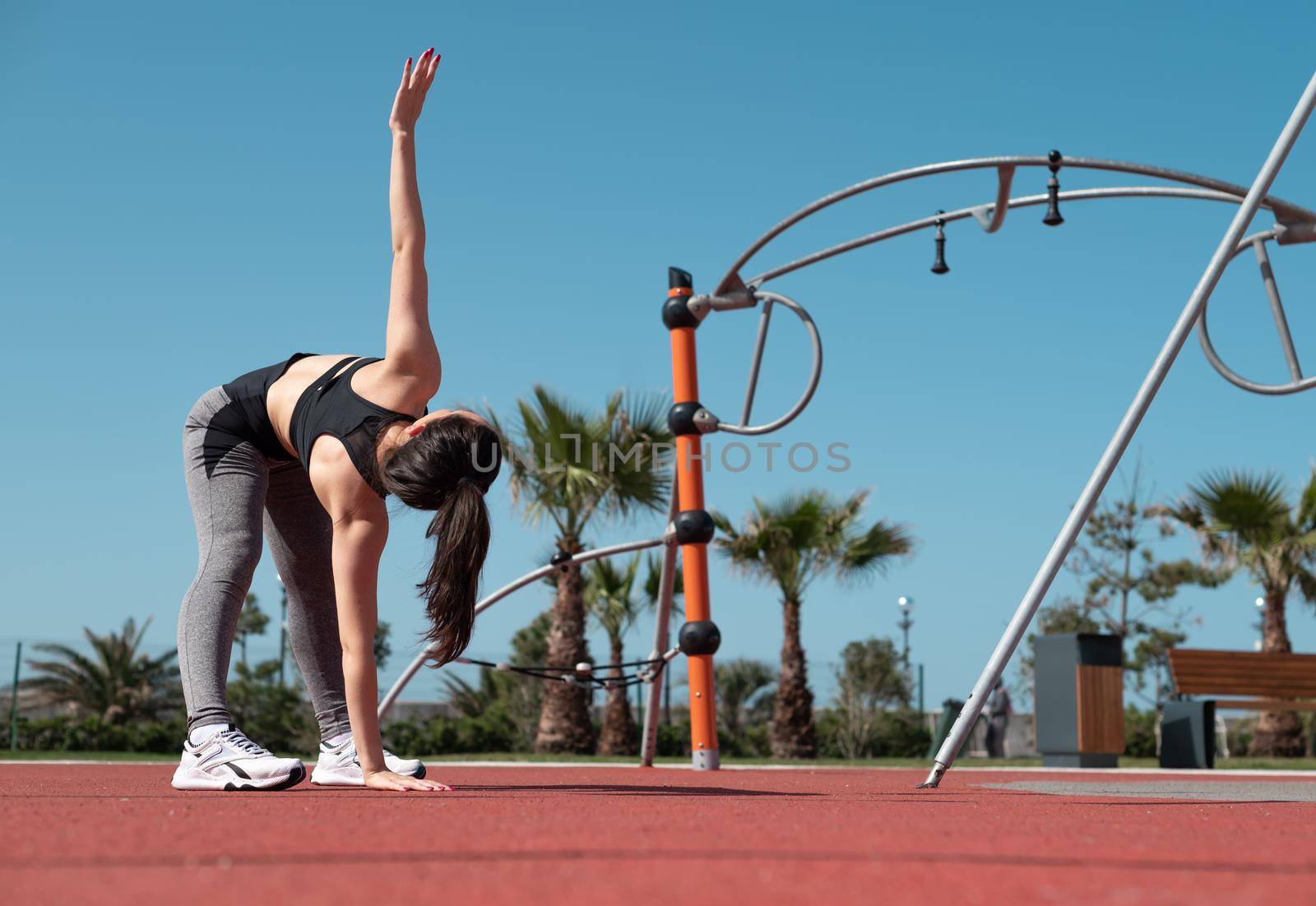 a sporty girl does fitness on a sports field in the summer outdoors by Rotozey