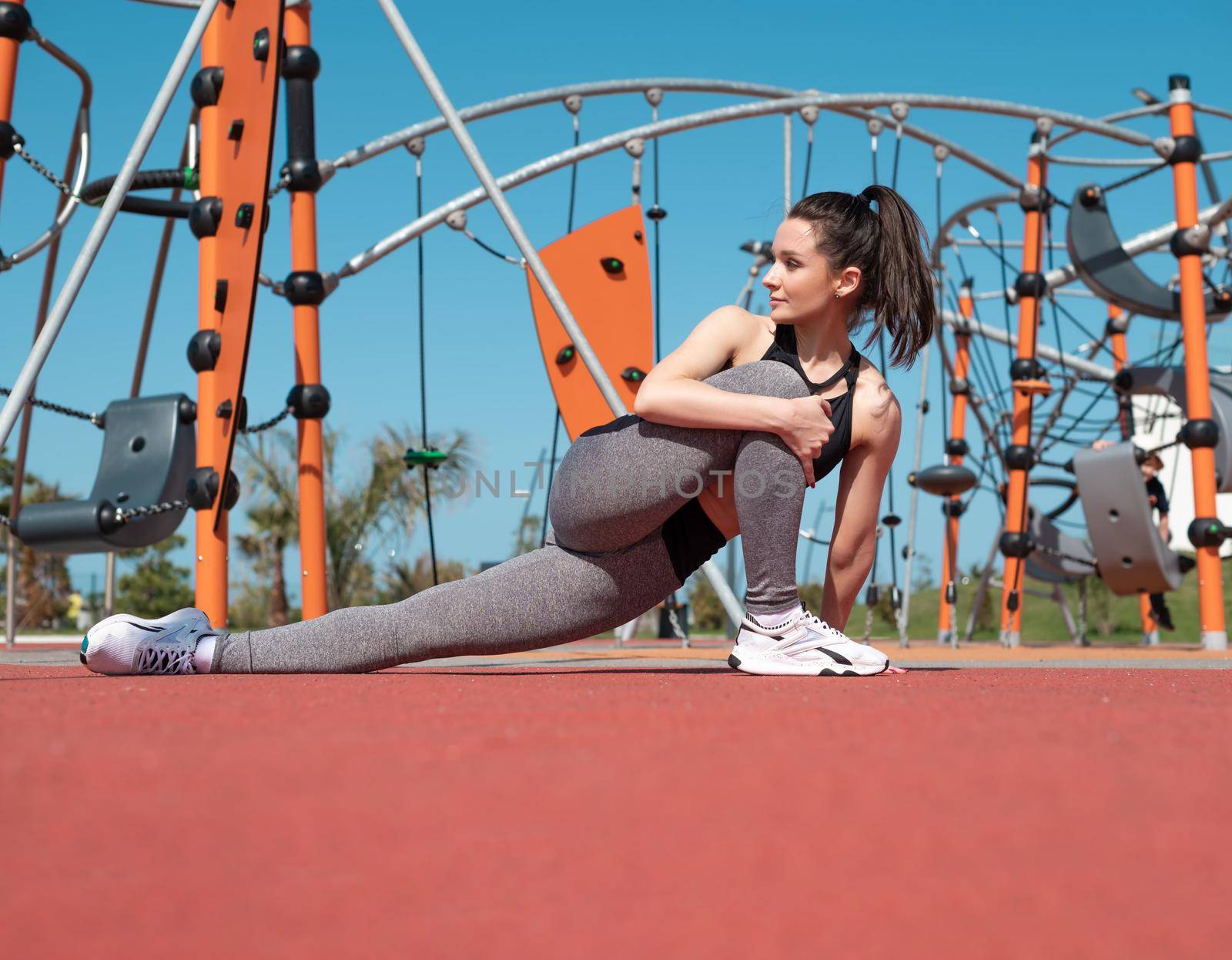 a sporty girl does fitness on a sports field in the summer outdoors by Rotozey