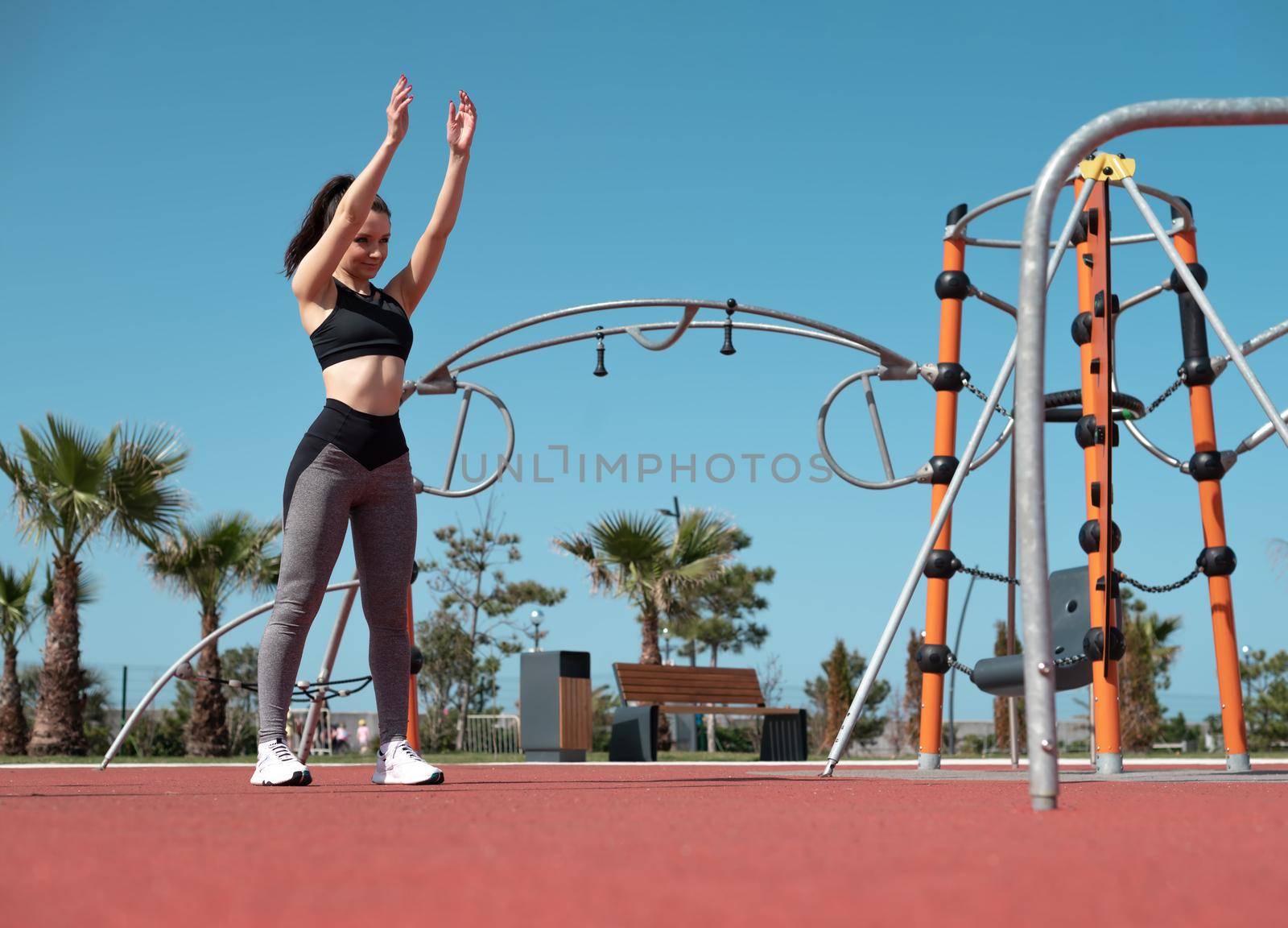 a sporty girl does fitness on a sports field in the summer outdoors by Rotozey