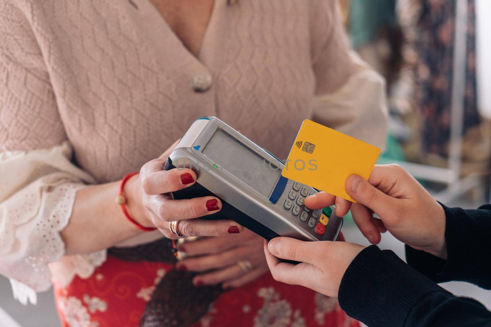 hands of a young woman shopping with a credit card. woman paying with contactless. concept of shopping. natural light, horizontal view, young woman shopping, mature woman business owner, close-up