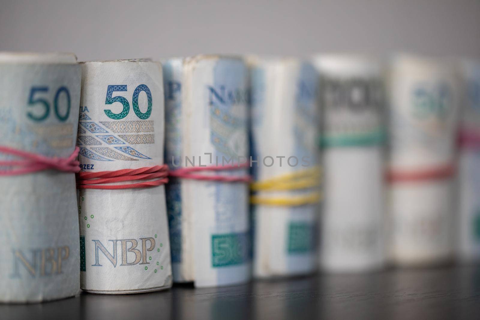 Oblique view of several rolls of fifty and one hundred zloty banknotes. Poland's national paper cash.