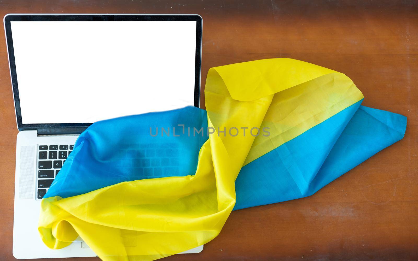 Laptop with blank screen on table and Ukrainian national flag on background, space for text. by Andelov13