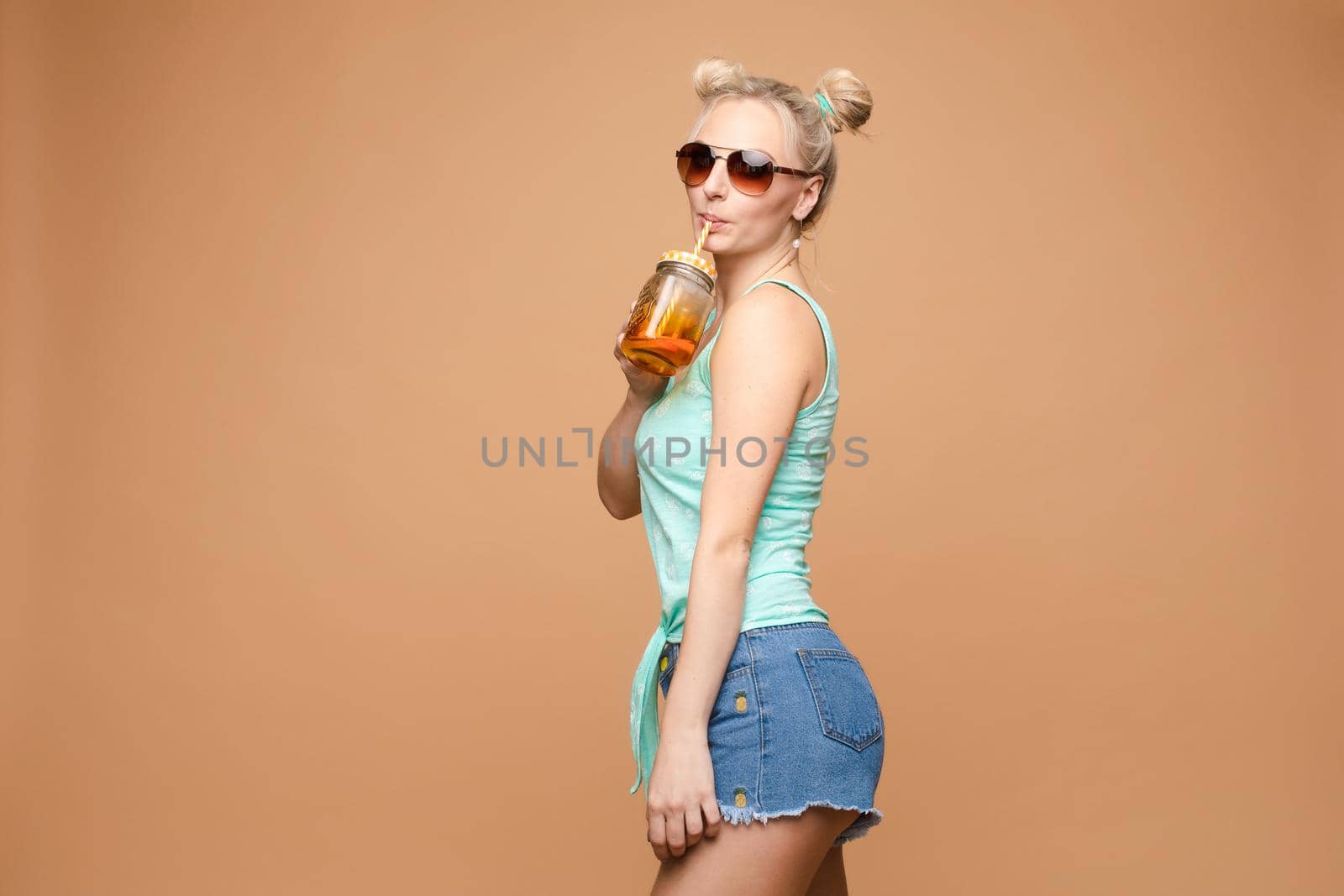 A beautiful woman in a bright outfit, denim shorts in the studio. Summer